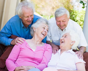 group of senior friends sitting outside laughing together