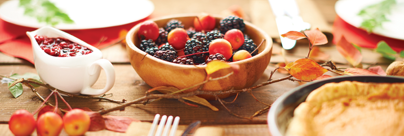 table decorated for fall with a bowl of berries and a pumpkin pie