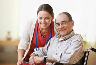 older gentleman sitting in a chair while female nurse leans over for photo with him
