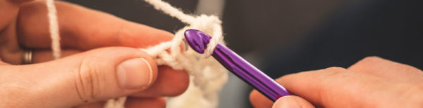 close up photo of woman crocheting with white yarn