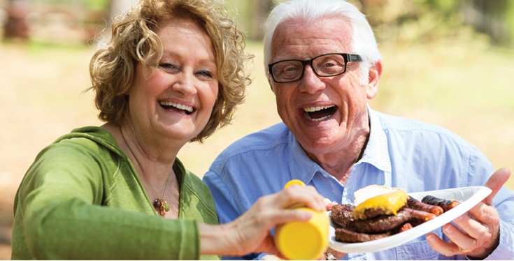 senior man and senior woman eating at a picnic table