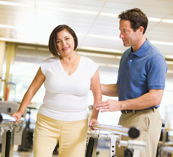 physical therapist helping middle age woman walk