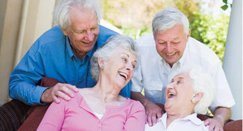 group of senior friends sitting outside laughing together