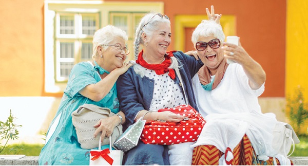 three senior women taking photos together outside