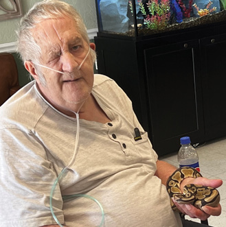 older adult man sitting in chair, smiling for photo. Terry, Resident of Fordsville.