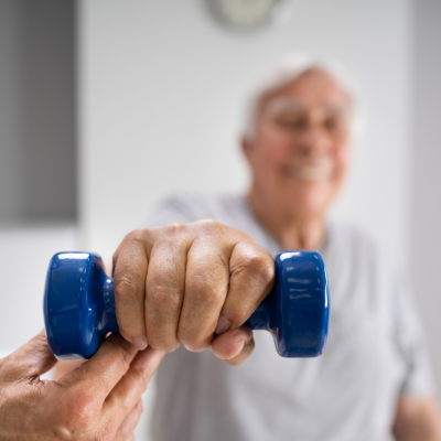 senior man in physical therapy working with light free weights